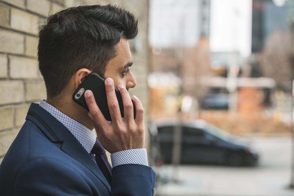 Une personne en costume passe un appel téléphonique dans la rue
