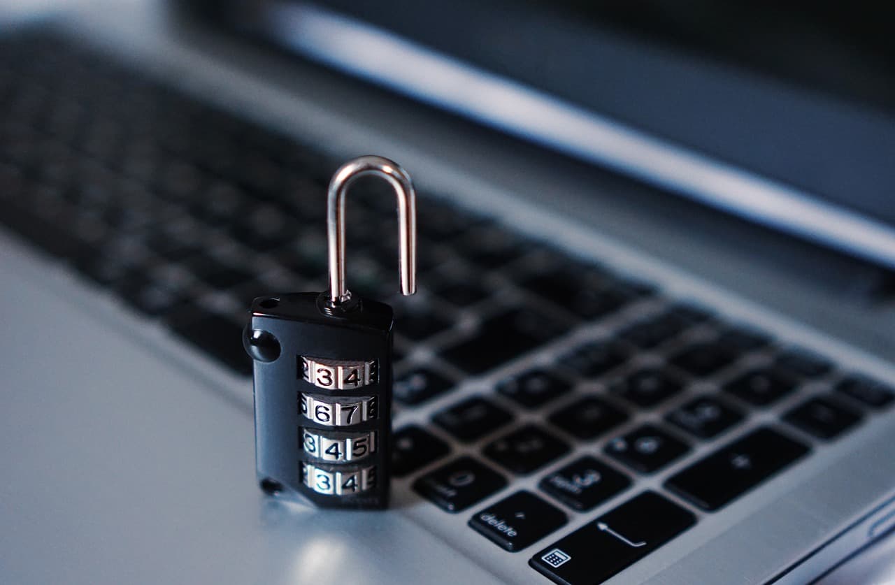Un cadenas à code, ouvert, posé sur le clavier d'un ordinateur portable